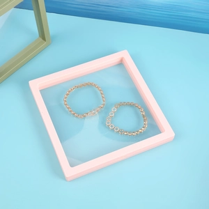 Detailed macro view of two gold linked bracelets inside a pink PE film display box