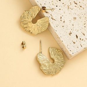 Irregular bohemian 14K gold plated ruffled earrings on a minimalist stone display pedestal