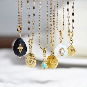 Macro detail of gold stainless steel pendants with evil eye and natural stone charms