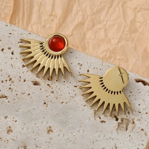 Detailed view of fan-shaped gold earrings featuring natural red stone on stone texture