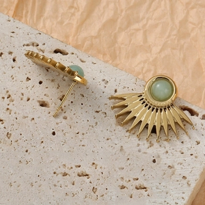 Exaggerated fan-shaped gold earrings with light green natural stone on travertine