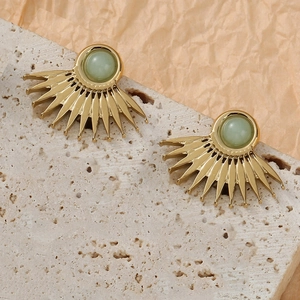 Elegant gold fan-shaped stud earrings featuring green gemstone on travertine stone