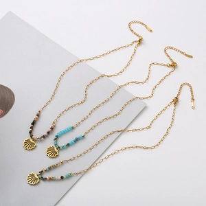 Detail of bohemian gold paperclip necklaces with colorful beads and shell pendants