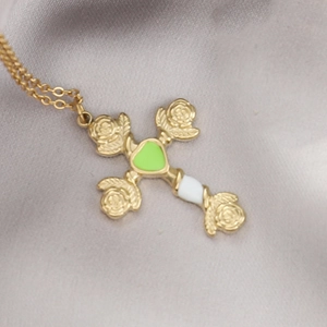 Nahaufnahme von Goldkreuz-Anhänger mit Rosenreliefs und grüner Emaille auf Satin