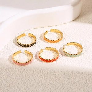 Set di cinque anelli in titanio dorato con punti in smalto colorato e bordi ondulati