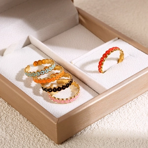Set di cinque anelli in smalto colorato placcati in oro in un portagioie beige