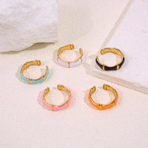 Detail of five colorful enamel bamboo style open rings in gold finish on stone