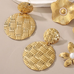 Golden flower earrings and textured hoop set on minimalist background for women