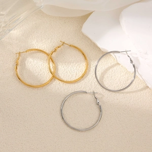 Minimalistische Creolen aus 18K Gold und Silber Edelstahl auf Stein Hintergrund