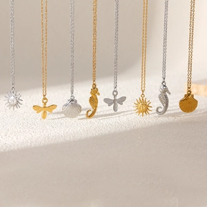 Detailed close-up of nature-themed sun, bee, shell and seahorse pendants on gold chains