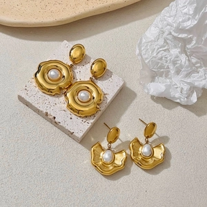 Detailed macro view of retro gold irregular metal earrings featuring elegant white pearls
