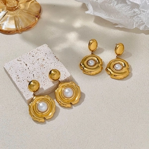 Detail of gold flower earrings with pearls on aesthetic stone and glass display