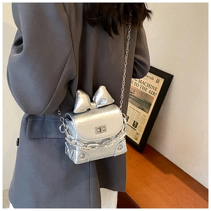 Macro detail of silver metallic bow on a pleated leather mini crossbody box bag