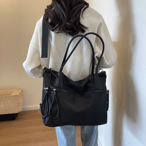 Large black nylon tote bag with leather handles shown on a model for size and style