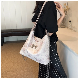 Close-up of stylish white butterfly print tote bag with silver bow and chain strap