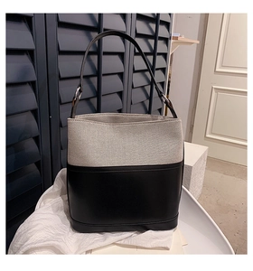 Detail of the two-tone bucket bag with grey canvas and black leather patchwork