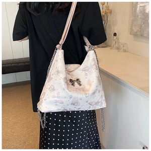 Detail of butterfly print and metal bow on cream large capacity patent tote bag