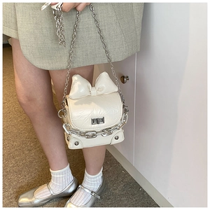 Detail of cream mini bow bag with wrinkled texture, chain strap, and turn-lock closure