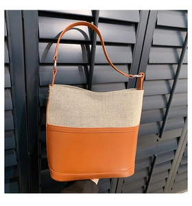 Detail of stitched leather and canvas bucket bag with silver metal ring buckle