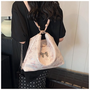 Detail of pink butterfly print tote bag showing silver bow accent and versatile straps