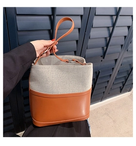 Close-up of a stylish bucket bag featuring mixed fabric and brown leather textures