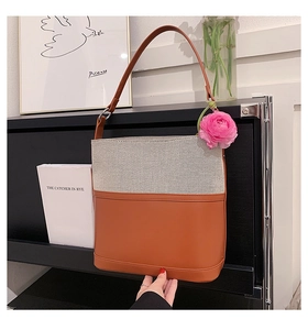 Detail of canvas bucket bag with brown leather trim and shoulder strap on a display