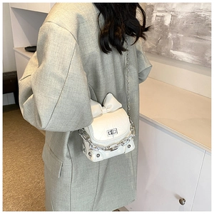 Detailed view of white quilted mini box bag with large bow and silver chain strap