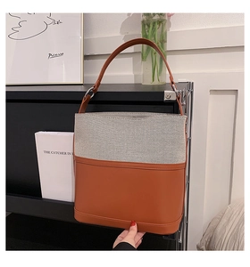 Detail view of contrast color bucket bag with tweed fabric and leather paneling