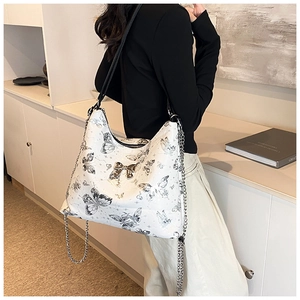 Detailed shot of white tote bag with black butterfly prints and silver metal chain strap