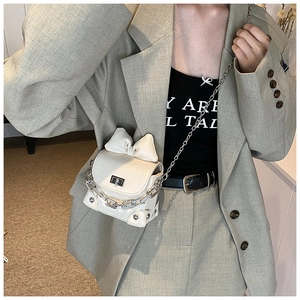 Close-up of a mini cream bow bag featuring silver chain strap and metal twist lock
