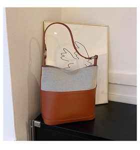 Close-up of beige canvas and brown leather bucket bag with silver metal ring