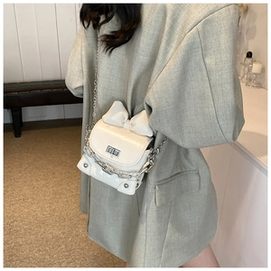 Close-up of cream mini box bag with 3D bow detail and silver chain strap