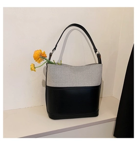 Detail of two-tone bucket bag featuring grey canvas texture and smooth black leather base