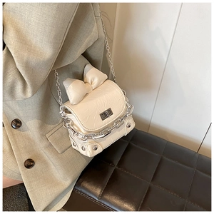 Detailed view of cream bow crossbody bag with silver chunky chain and square twist lock