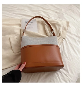 Close-up of contrast stitching bucket bag featuring brown leather and canvas materials
