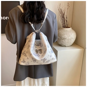 Rear view of model wearing white butterfly print tote bag with silver chain straps