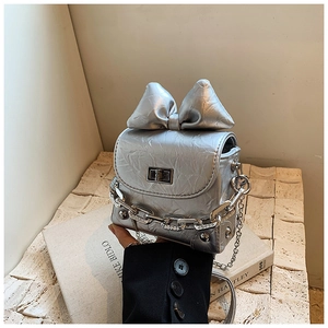 Close-up of metallic silver mini box bag with crinkled leather and large bow detail