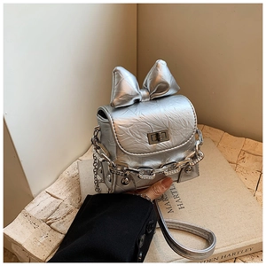Detail of silver mini bow box bag with metallic texture, chunky chain, and twist lock