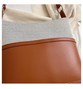 Detail of brown leather and cream canvas stitching with silver metal ring on bucket bag