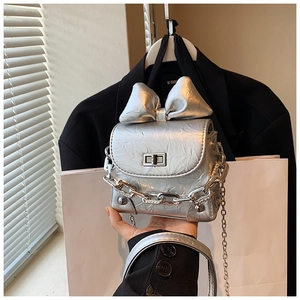 Detail of silver metallic mini bag with large bow decoration and silver chain strap