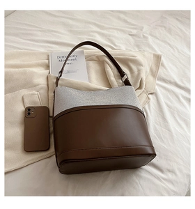 Detail of coffee brown leather and off-white tweed fabric on a stylish bucket bag