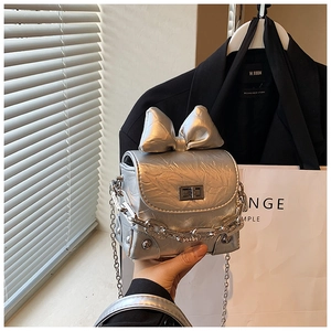 Detailed shot of silver mini crossbody bag with oversized bow and metallic chain strap