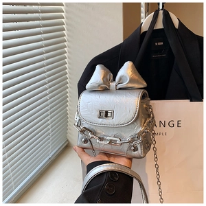 Detailed view of silver bow-knot box bag with wrinkled leather and metal chain