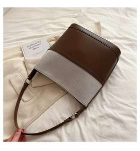 Detail of large canvas and brown leather bucket bag on a cozy cream textured background