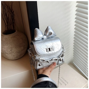 Detail of silver pleated leather mini bag with bow accent and chain straps