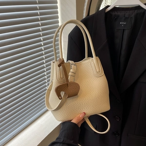 Elegant cream lychee pattern bucket bag with brown elephant charm in soft indoor lighting