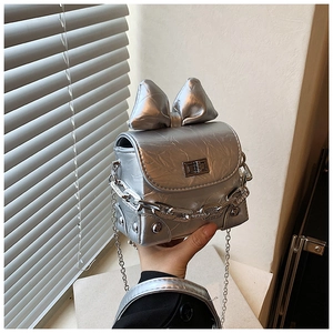 Detailed shot of silver mini crossbody bag with a metallic bow and chain strap detail