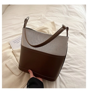 Detail of two-tone bucket bag featuring dark brown leather and beige woven fabric texture