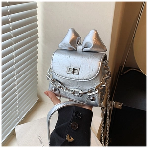 Detail showing shiny silver wrinkled patent leather texture and metal chain of the bow bag