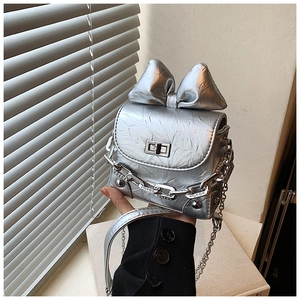 Close-up of silver mini box bag featuring a large bow and metallic crinkled texture